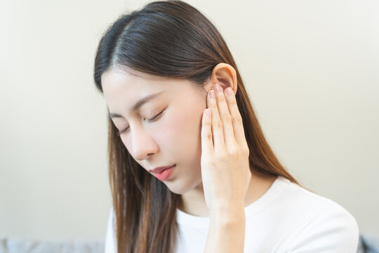 Tinnitus concept, sick asian young woman, girl have ear pain or earache, hand touch plug ear, suffering painful otitis from loud of noisy sound, inflammation. Health care nerve deaf eardrum disease.