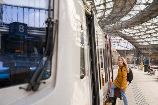 Woman Looking At Camera While Boarding Train at Station 