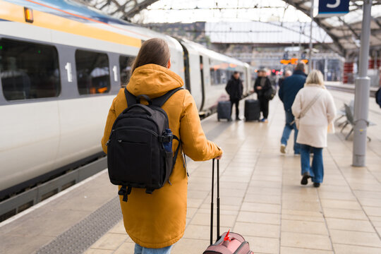 Woman Walking at Busy Train Station With Suitcase 