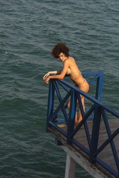 Woman poses on a wooden deck overlooking the water 