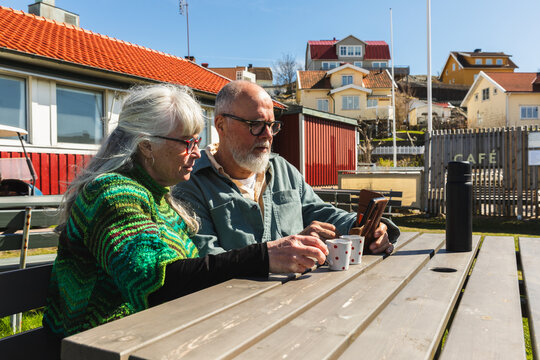 Senior Couple Looking at Smartphone During Coffee Break