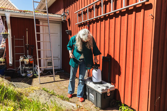 Mature Woman Preparing Pressure Sprayer for Cleaning