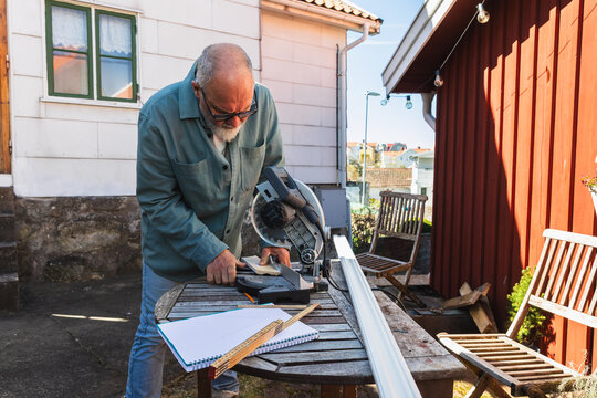 Mature Handyman Positioning Wood in Miter Saw