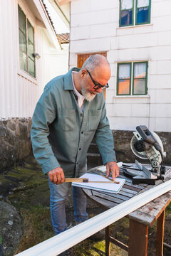 Mature Man Measuring Wood Trim with Folding Ruler