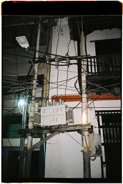Wires and a transformer sit near a building at night
