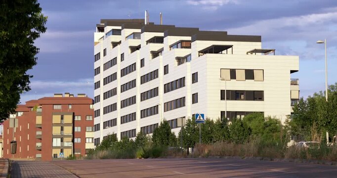 Modern white urban building with contemporary architecture, large windows and geometric facade design. City development and modern construction in Madrid, Spain under dramatic evening clouds.