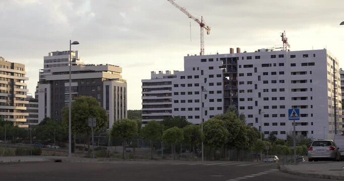 Modern residential buildings and urban development project with construction cranes in Madrid, Spain. Contemporary housing expansion with apartment blocks, city infrastructure and evening light.
