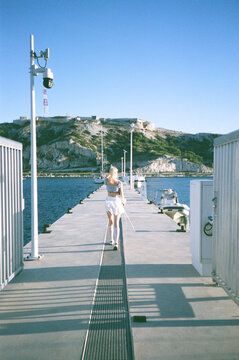 Woman walks on dock near water and boats in daylight