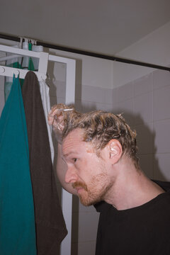 Man applying hair product in bathroom 