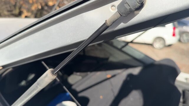 Gas strut extends and compresses as the car trunk lid opens and closes, hatch support mechanism, cargo access, automotive maintenance, vehicle operation.