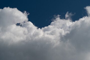 Fototapeta premium Dramatic white cumulus clouds against deep blue sky