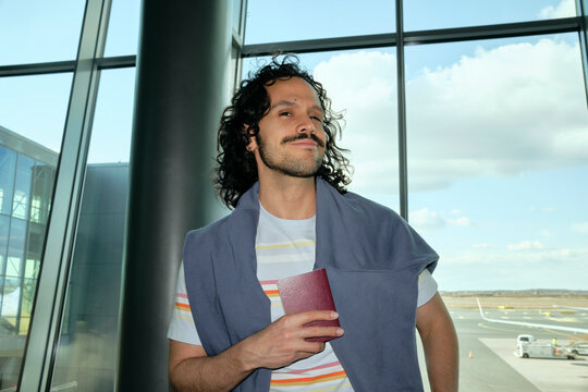 Man holding passport inside Helsinki Airport terminal
