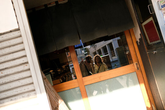 Friends reflected in restaurant doorway in Tokyo