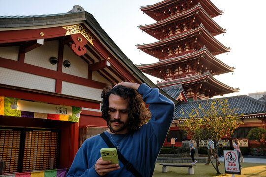 Traveler using smartphone beside Tokyo temple pagoda