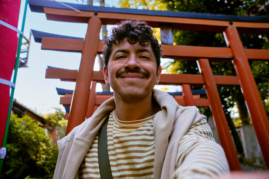 Smiling traveler taking selfie near red torii gates in Tokyo