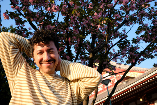Traveler posing beneath blooming sakura trees in Tokyo