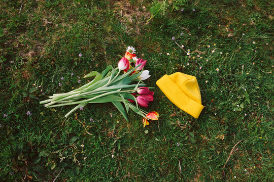 Bright flowers and a yellow hat on green grass