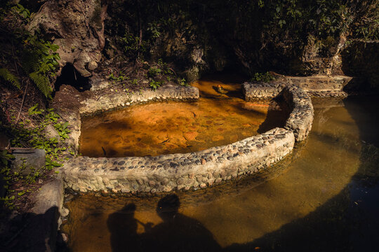 Mineral water source surrounded by rocks at Peguche waterfall in Otavalo, Ecuador