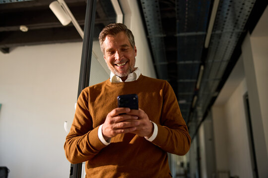 Employee smiles while uses his phone in the hallway