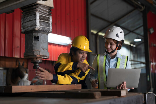 Male and female engineer at work, inspecting or maintenance vertical drilling machine in factory