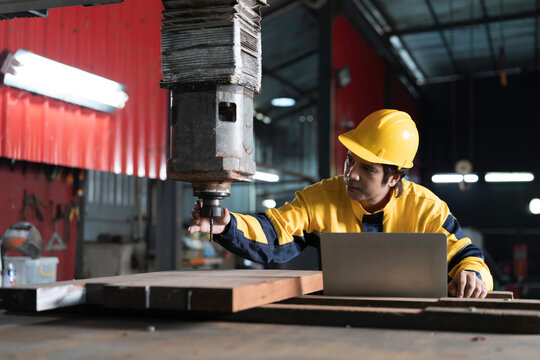 Industrial worker at work, inspecting or maintenance vertical drilling machine in factory