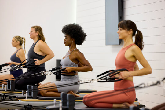 Four women engage in a pilates class inside a fitness studio
