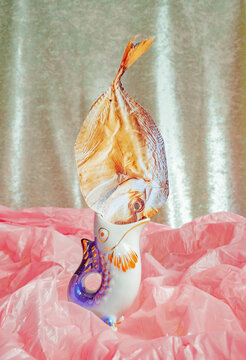 Unique fish sculpture stands on pink crumpled paper background