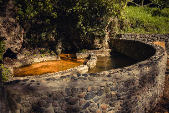 Mineral water source surrounded by rocks at Peguche waterfall in Otavalo, Ecuador