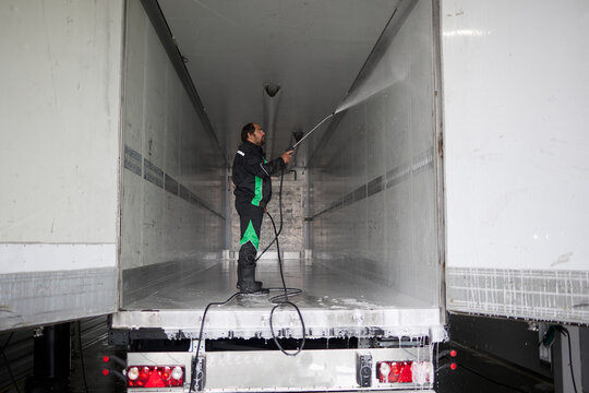 A skilled truck cleaning professional meticulously washes a semi-trailer truck, showcasing their expertise and attention to detail in maintaining vehicle cleanliness and appearance.