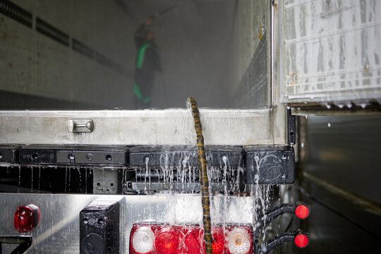 A dedicated man in overalls meticulously cleans the interior of a heavy truck semi-trailer, showcasing his professionalism and attention to detail in maintaining vehicle cleanliness.