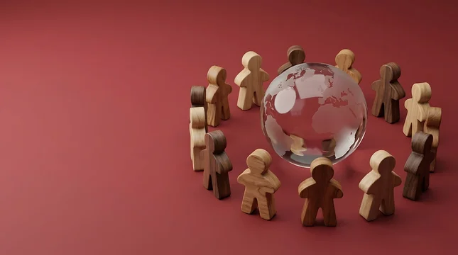Wooden human figures standing in a circle around a glass globe on red background