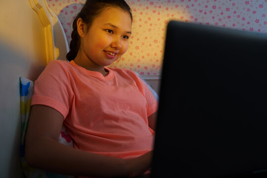 Teenage girl using laptop gadget at home in sunset light