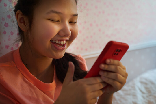 Teen girl smiling at smartphone while light glows at sunset