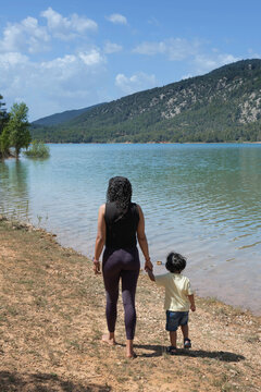 Mother and son walking along a calm lake shore on holiday