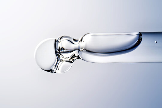 Skincare liquid serum dropping from glass pipette