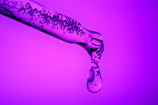 Skincare serum dropper with purple liquid dropping