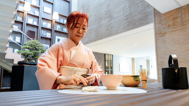Japanese woman preparing matcha tea in serene tea room