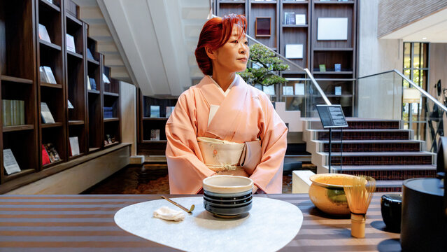 Japanese woman in kimono preparing to make matcha tea indoors