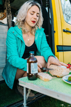 Woman enjoying holiday snack at camper van outdoor table