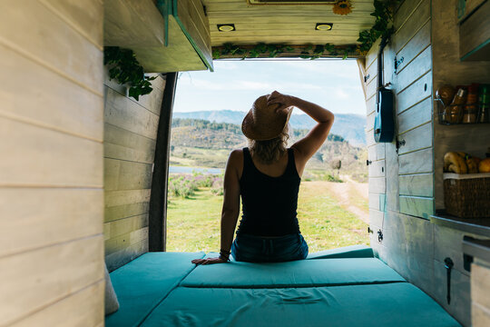 Woman enjoying holiday view from camper van bed at dawn
