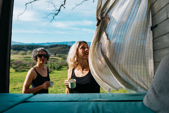 Women enjoying morning coffee outside camper on holiday
