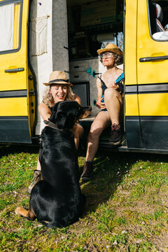Women relaxing by camper with ukulele on holiday trip
