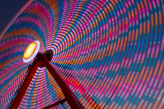 Long exposure ferris wheel spinning colorful lights at night