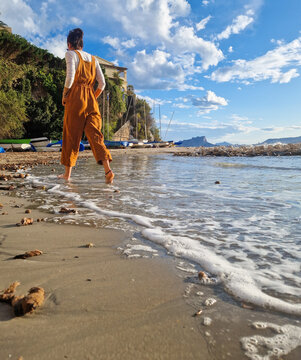 Woman walking along Mediterranean beach at sunny summer shore