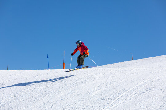 Skier gliding down snowy mountain under blue sky