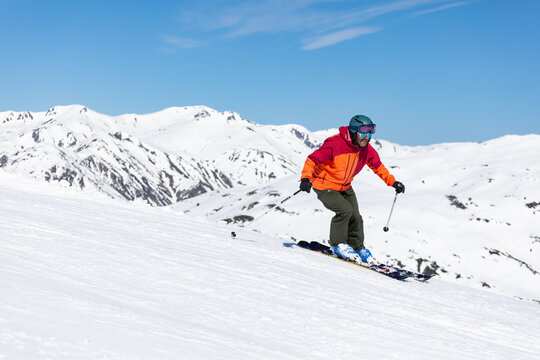 Skier navigating snowy mountain slopes in bright gear