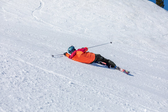 Ski enthusiast falls in bright snow-covered mountains