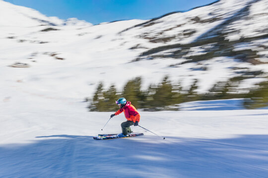 Skier speeding down snowy mountain slope