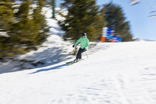 Skier navigating snowy slope with trees in background