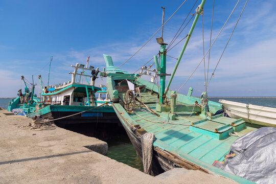 Fishing boats moored at Banda Aceh harbor under blue sky